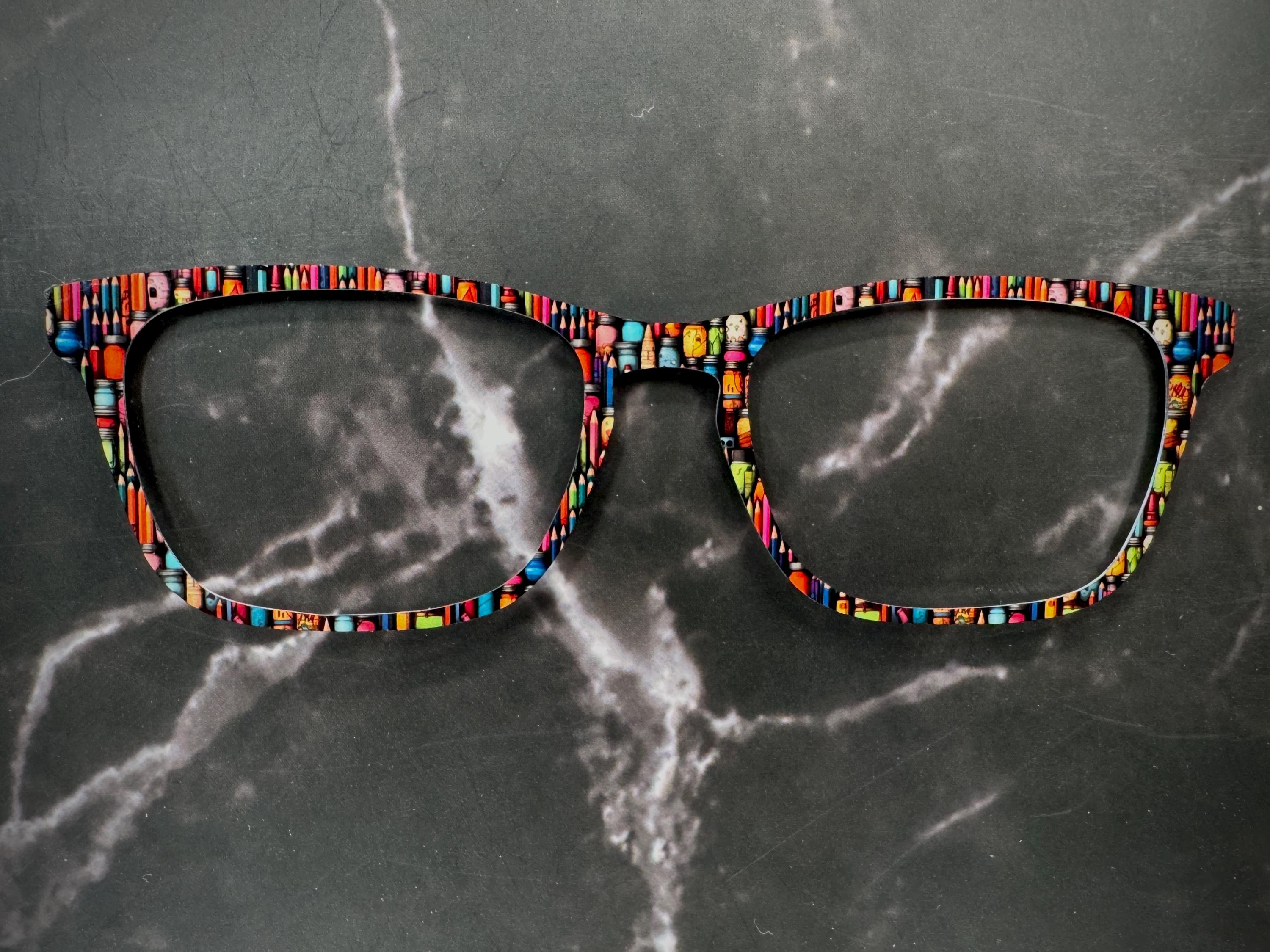 artists pencils and paints on a metal topper for pair eyewear.